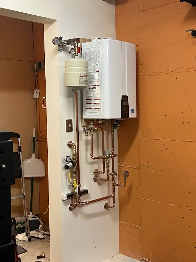 Plumbing technician inspecting water heater connections in Rutland